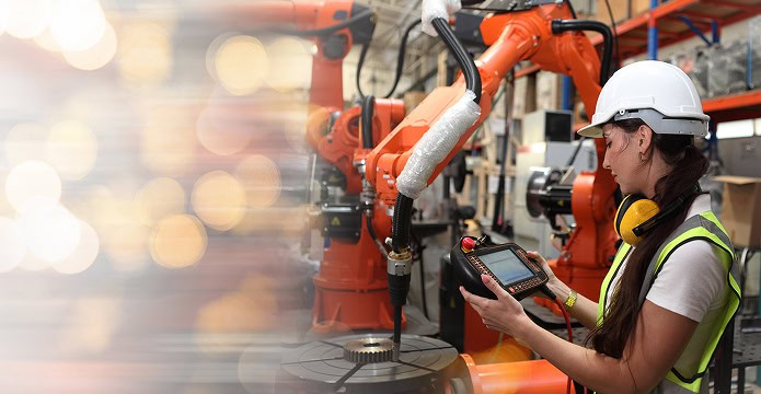 A woman working on a robot assembly arm in a factory.