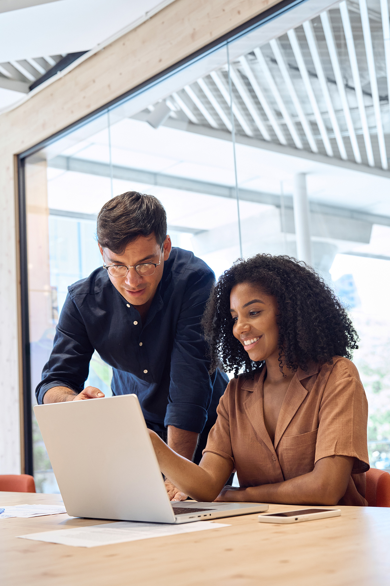 A man and a woman looking at a laptop in an office environment.