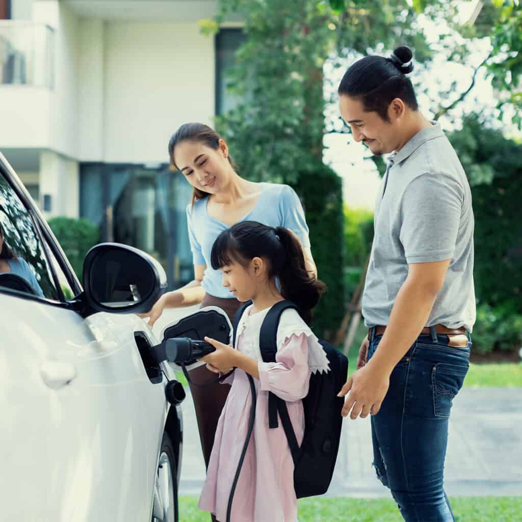 Family charging electric vehicle together outside in a suburban neighborhood